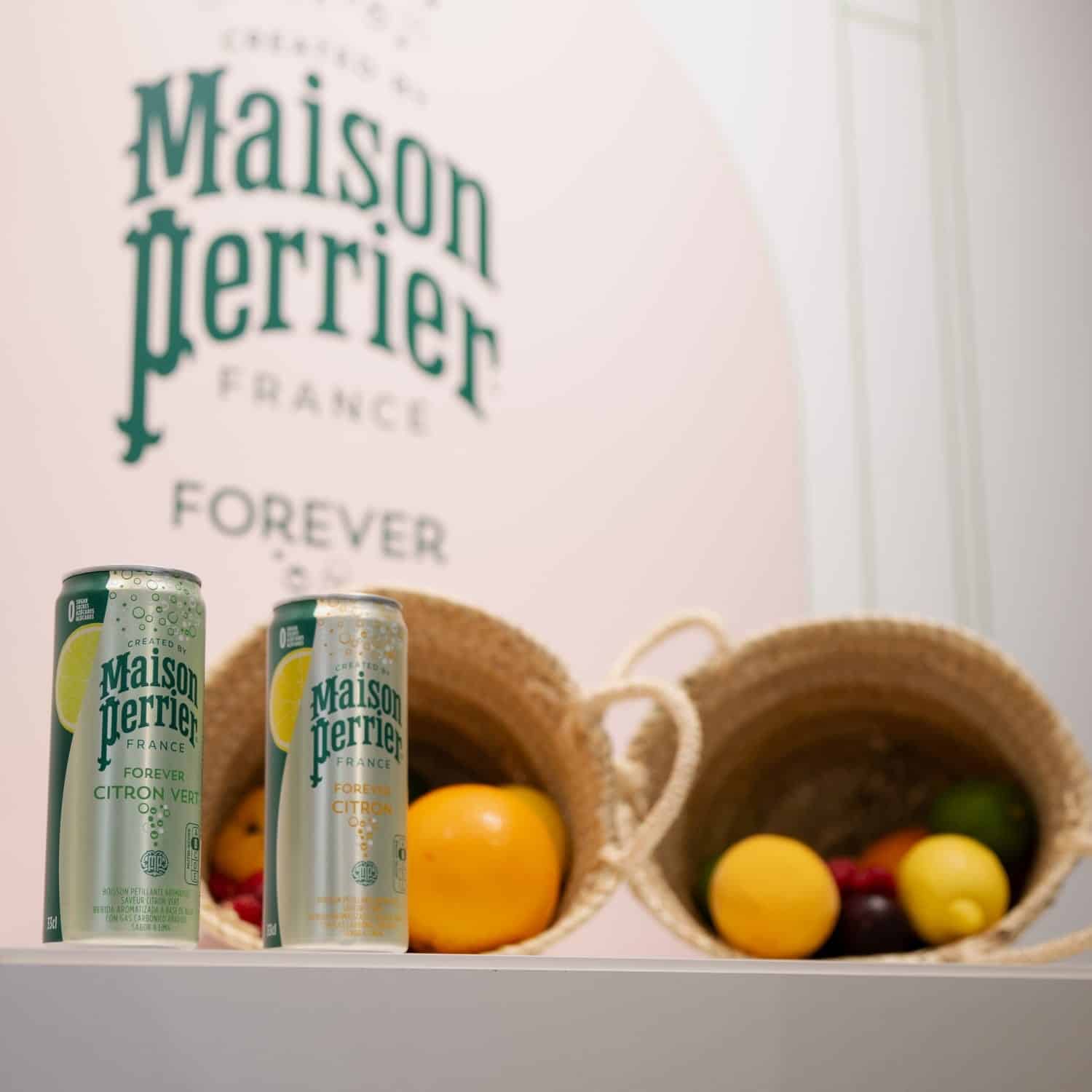 Latas de Maison Perrier con frutas de fondo